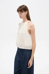 Musculosa sin mangas color natural, confeccionada en viscosa, con cuello redondo base con frunces y elástico en la parte inferior.