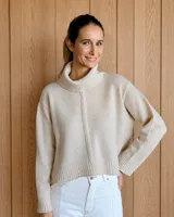Sweater de lana lambswool en color beige, con cuello alto tipo polera, diseño holgado y costura vertical central en el frente.