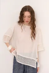 Blusa de corte holgado color blanco, de manga corta con detalles de encaje en las mangas y el dobladillo inferior.