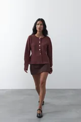 Cardigan negro de tejido de punto con cuello redondo y cierre frontal con botones a contraste. Presenta un corte entallado en la cintura con una silueta levemente evasé y mangas largas.