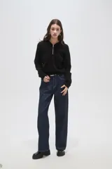 Sweater negro de punto con capucha, cierre frontal parcial y mangas largas. Presenta un diseño de tejido acanalado en la zona del cuello y los hombros.
