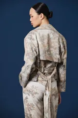 Saco Spencer de mujer, corto y de silueta relajada, con solapas amplias y bolsillos. Cuenta con un estampado estilo paisaje boscoso en tonos beige, gris y marrón, y un parche bordado con la marca en el puño izquierdo.