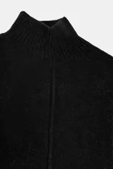 Vestido corto de punto con cuello subido, manga larga y sisa ancha. Presenta un detalle de costura vertical marcada en el centro del delantero y acabados en rib en cuello, puños y ruedo.