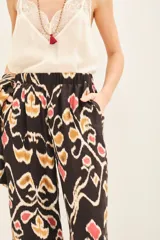Pantalon de corte recto y fluido, confeccionado en una mezcla de viscosa y seda. Presenta un estampado étnico multicolor sobre fondo oscuro y cuenta con cintura elastizada para mayor comodidad.