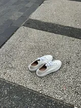 Championes blancos de cuero liso, con cordones y suela plana.