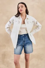 Sobrecamisa blanca de algodón con bordados florales calados en mangas, cuello y pechera. Corte oversize, manga larga y dos bolsillos frontales.