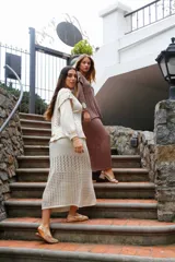 Pollera midi color crudo, tejida en hilo de algodón con calados horizontales. Tiene silueta recta, abertura frontal, elástico en la cintura y tiras regulables.