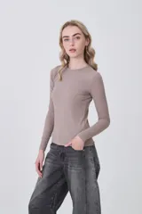 Remera de manga larga ajustada al cuerpo, color blanco, con cuello redondo bajo y tejido acanalado.