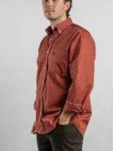 Camisa de corte regular color azul marino, confeccionada en algodón. Presenta cuello con botones, cierre frontal abotonado y un bolsillo en el pecho con el logo de la marca bordado en color rojo.