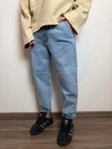 Jean de corte slouchy con tiro medio, confeccionado en denim de lavado claro. Presenta un diseño holgado en la parte superior que se estrecha hacia el tobillo, con ruedo doblado.