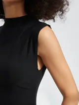 Vestido corto negro de corte ajustado, sin mangas, con cuello alto y frunces laterales.