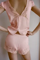Shorts de tiro medio confeccionado en satén, con detalle de encaje y bordados florales a contraste en el ruedo. Presenta cierre lateral con botones.