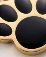 Dije de acero dorado con forma de huella de mascota, con relleno esmaltado en color negro.