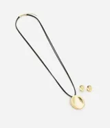 Conjunto de bijouterie compuesto por un collar largo con cordón negro y dije metálico redondeado, junto con un par de aros a juego de diseño minimalista.