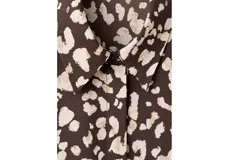 Camisa de poliéster con estampado animal print abstracto en tonos marrones y beige, cuello camisero, manga larga y cierre frontal con botones.