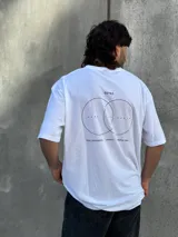 Remera blanca de corte oversize con estampado en la espalda que incluye dos círculos intersecados con las palabras 'Surf', 'Life' y 'Skate', y las frases 'Real Experience', 'Coexist' y 'Meaningful Day'.
