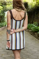 Vestido corto blanco con rayas verticales en azul, amarillo y marrón. Tiene escote redondo, breteles anchos y corte holgado.