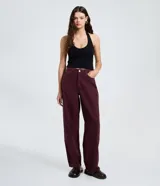 Pantalón baggy de sarga color bordó, con cintura tradicional, cierre de botón y cremallera, bolsillos curvos y corte recto y holgado.