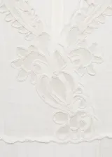 Vestido corto de color crudo con escote en pico y mangas cortas. Presenta un diseño de tejido con textura de cuadros y detalles bordados calados en el escote, las mangas y el ruedo. Cuenta con un corte recto y cierre de cremallera invisible en la parte posterior.