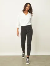 Jean de corte skinny en color azul medio, con tiro medio, cierre frontal con botón y bolsillos laterales y traseros.