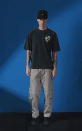 Remera de algodón premium con efecto nevado, corte oversize y cuello redondo. Presenta una estampa gráfica en la espalda con motivos de escorpión, rosa y tipografía en color crema.