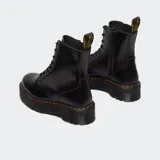 Botas de caña alta estilo militar Dr. Martens modelo Jadon, confeccionadas en piel negra con acabado brillante. Presentan cierre de cordones, suela de plataforma dentada con costuras amarillas características y tirador trasero con logo.