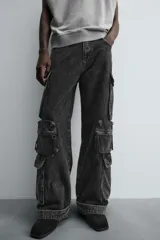 Pantalón cargo de denim lavado negro, corte relajado y tiro medio. Presenta múltiples bolsillos cargo con solapa y detalle de cierre en las perneras, además de bolsillos de vivo traseros. El bajo es ajustable con trabilla.