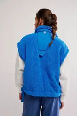 Chaleco de fleece color azul, de silueta oversized, con cierre frontal mediante botones a presión y bolsillos delanteros.