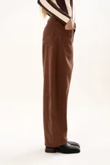 Pantalon de tiro medio con silueta curvada, mas ancha en la zona del muslo y la rodilla, con bolsillos laterales y cierre frontal con cremallera y boton.