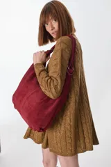 Bolso hobo de cuero gamuzado color marrón, con correa de hombro y cierre superior.