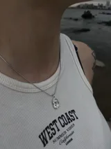 Collar plateado con cadena fina y dije ovalado con relieve de una rosa.