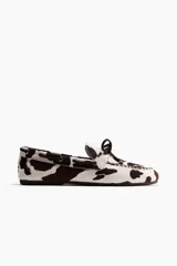 Zapatos náuticos de cuero con estampado animal print tipo vaca, con cordones delanteros y costuras decorativas.