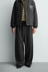 Pantalón de corte baggy fit, color gris oscuro con estampado de rayas verticales finas. Presenta cintura elástica con cordón interior, bolsillos frontales de vivo y bolsillos traseros de plastrón.