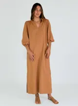 Vestido largo color celeste, de corte recto y mangas 3/4 abullonadas con puños elásticos. Escote en V. Confeccionado en algodón. Presenta aberturas laterales en el ruedo.