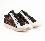 Zapatilla de cuero vacuno con diseño de caña media, combinando paneles en negro, blanco y un estampado animal print de tigre en tonos marrones. Presenta un aplique lateral en forma de estrella, cordones negros y suela de goma con efecto desgastado.