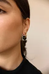 Aros de acero quirúrgico dorado con dije colgante en forma de argolla de piedra natural negra con destellos.