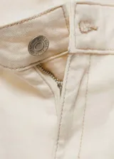 Jeans de tiro medio color blanco roto, estilo acampanado, con bolsillos de parche delanteros y traseros, trabillas para cinturón y cierre frontal con cremallera y botón.