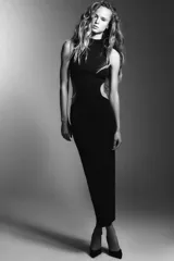 Vestido largo de corte recto con cuello perkins y diseño sin mangas. Presenta aberturas laterales (cut out) en la cintura con detalles de aplicaciones de pedrería tipo joya.