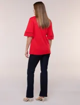 Remera blanca de silueta recta y algodón suave, con escote redondo y pequeña abertura central tipo gota. Presenta mangas de largo intermedio con aplicación horizontal de puntilla calada al tono y ruedo recto con tajos laterales.