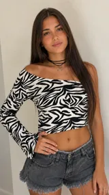 Top cropped de manga larga con diseño asimétrico de un solo hombro y estampado animal print estilo cebra en blanco y negro.