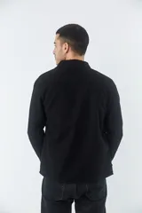 Sobrecamisa de jean color tostado, con cuello clásico, cierre frontal con botones y dos bolsillos frontales con solapa. Presenta mangas largas con puños abotonados y un pequeño parche decorativo en el ruedo.