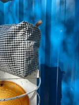Necessaire con estampado a cuadros blanco y negro, grifa de goma, detalles de cordón, cierre y bolsillo transparente interior.