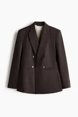 Blazer cruzado marrón oscuro con solapas de pico, hombreras y cierre frontal de doble botonadura. Cuenta con bolsillos con solapa en la parte delantera, puños con botones y forro interior.