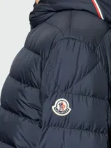 Campera puffer corta azul marino con capucha ajustable, cierre frontal y bolsillos laterales.