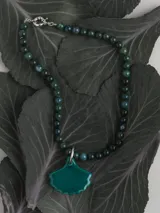 Collar de piedras naturales en tonos verdes y multicolores, con un gran dije de porcelana en forma de hoja en tono verde o naranja, unido mediante una argolla de acero.