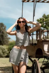 Conjunto de dos piezas compuesto por un chaleco corto con botones frontales y una falda corta tipo short con diseño cruzado, ambos con estampado de rayas verticales.