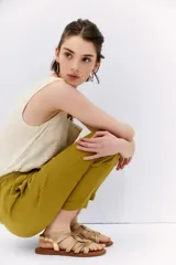 Pantalón tipo babucha de tiro alto, color verde mostaza, confeccionado en símil lino. Presenta cintura elastizada con lazo de ajuste y largo al tobillo.