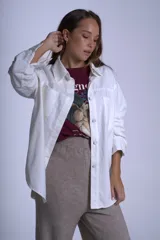 Sobrecamisa color beige confeccionada en gabardina, de corte holgado, con cuello camisero, cierre frontal con botones, dos bolsillos de parche en el pecho y mangas largas con puños abotonados.