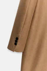 Abrigo largo negro ZARA Woman Collection de corte recto, confeccionado con hilatura de lana. Presenta cuello con solapa de muesca, cierre cruzado de doble botonadura frontal y bolsillos ribeteados en los laterales.