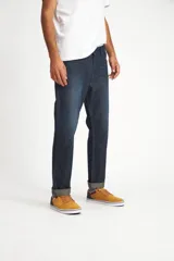 Pantalón de jean azul oscuro, corte recto, con ruedo doblado.